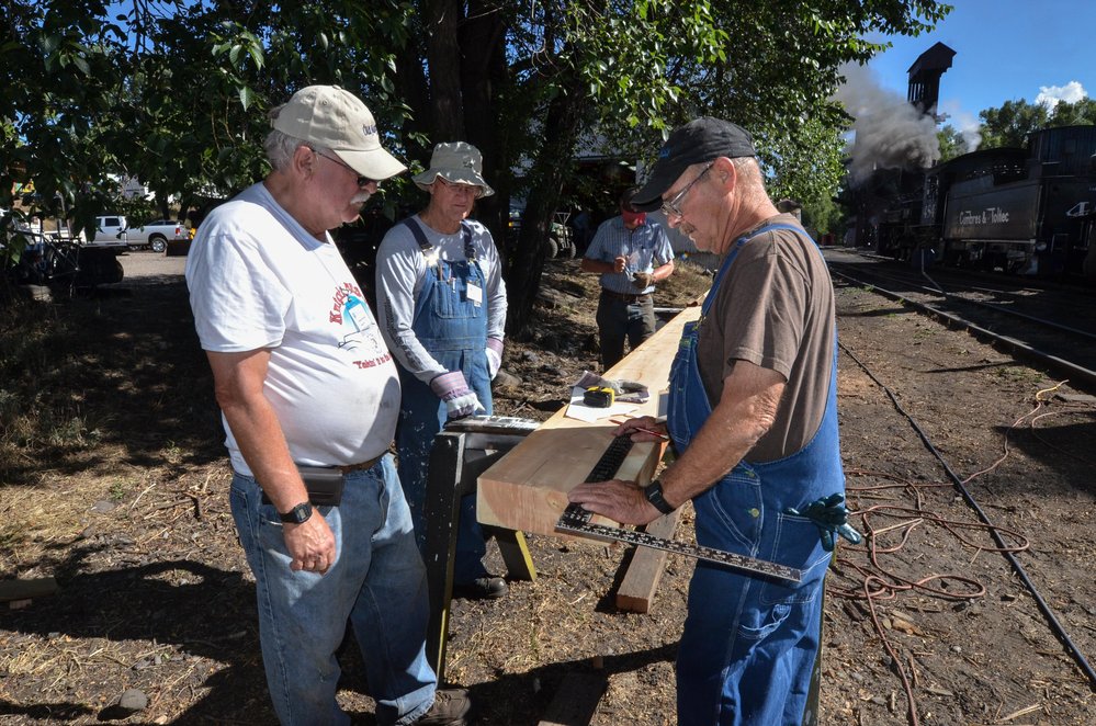 2018-07-25 A crew is under the shade tree marking a center beam for a car rebuild.jpg